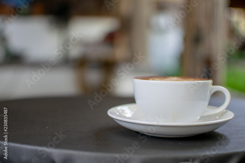 A white cup of coffee is placed on a gray table.