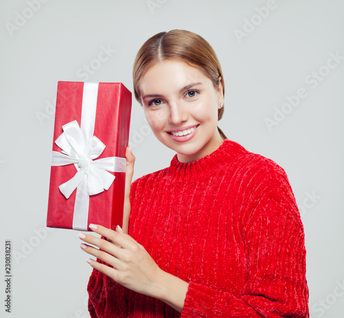 Young healthy woman in red sweater with gift box. Happy smiling female model