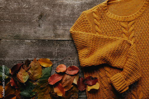 flat lay with fallen leaves and orange sweater on wooden tabletop