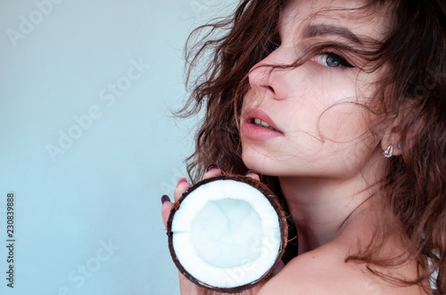 Young beautiful curly woman holding coconut. Skin and hair care concept