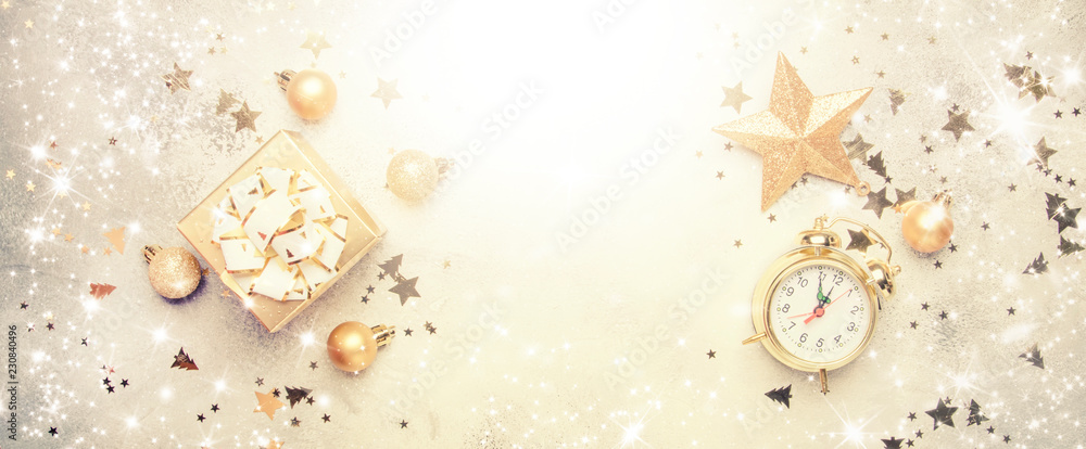 Christmas or New Year composition, frame, gray background with gold Christmas decorations, stars, snowflakes, balls, alarm clock, gift box, banner, top view Christmas or New Year composition, frame, gray background with gold Christmas decorations, stars, snowflakes, balls, alarm clock, gift box, banner, top view