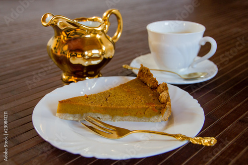 Slice of fresh home made pumpkin pie on wooden surface.  Traditionally served in fall or for thanksgiving in the United States.  Selective focus photo