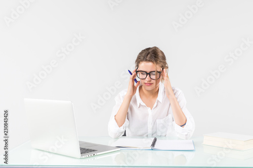 Young businesswoman suffering from headache in front of laptop at office desk isolated on white background