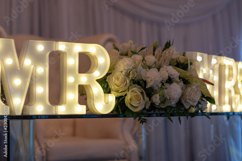 The bride and groom's table at the wedding reception with a Mr & Mrs LED sign