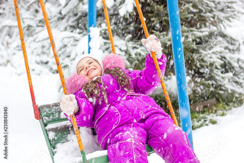 Little kid girl swinging on...
