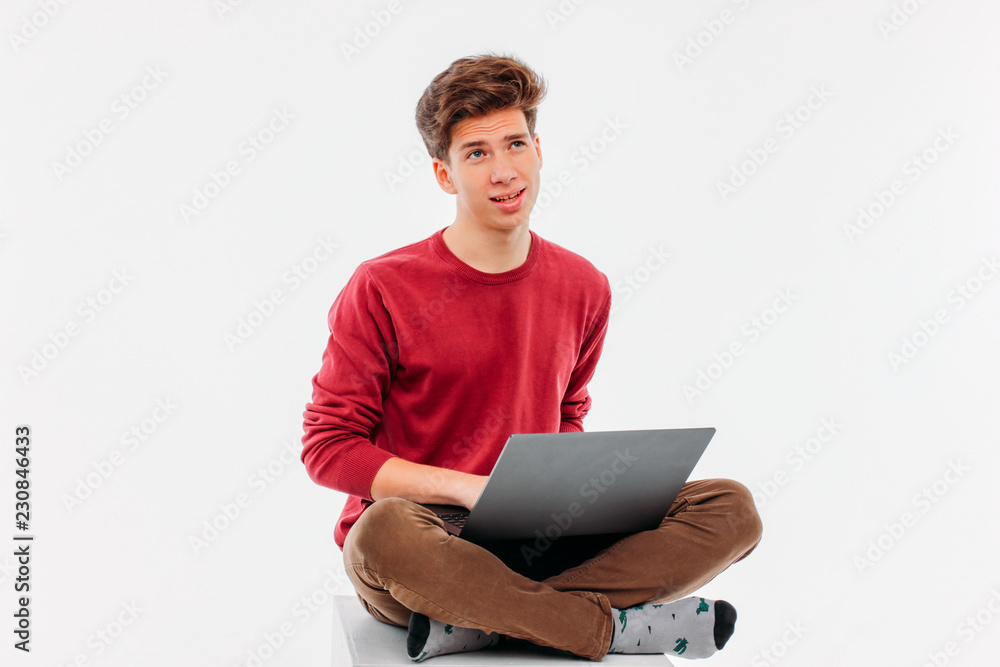 Teenager student thinking and working at laptop on white backgro