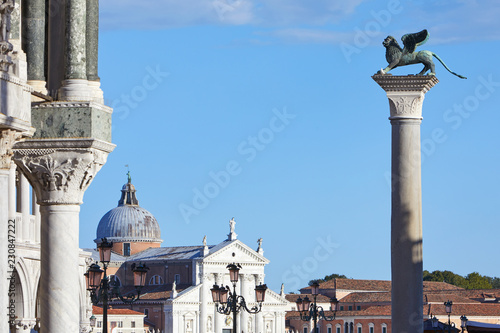 San Marco winged Lion statue on column and San Giorgio Maggiore basilica, blue sky in Italy