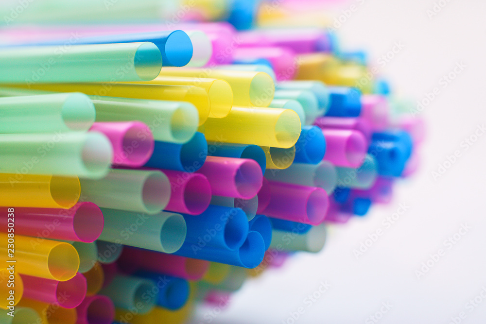 Close up on multiple plastic straws laying on a white background Close up on multiple plastic straws laying on a white background
