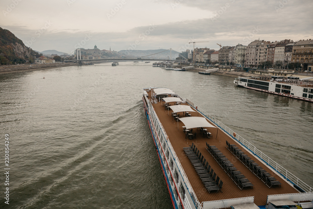 Cruiser arriving on the Danube river to the morning autumn Budapest in Hungary after the sunrise