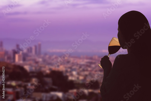 Female hand with glass of wine on the neighborhood of San Francisco city and bay background. Service on the roof of the restaurant