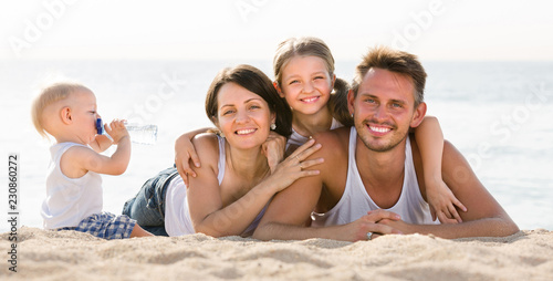 family of four lying together on beach vacation