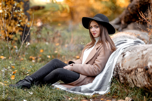 beautiful woman in black hat sitting under big tree