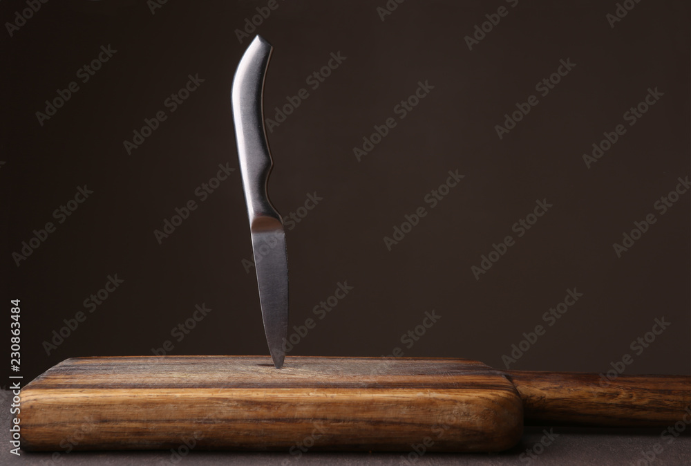 Knife stuck in cutting board on dark background. Wood cutting board and ...