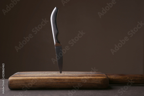 Obraz na plátně Knife stuck in cutting board on dark background