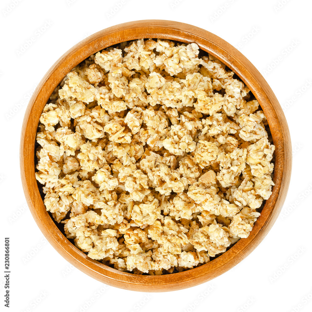 Crunchy granola in wooden bowl. Crispy cereals, made of rolled and toasted whole grain oat flakes and honey. Breakfast and snack food. Isolated macro food photo closeup from above on white background. Crunchy granola in wooden bowl. Crispy cereals, made of rolled and toasted whole grain oat flakes and honey. Breakfast and snack food. Isolated macro food photo closeup from above on white background.