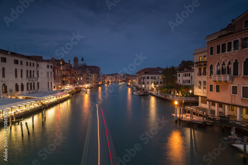 Night view on Grand Canal with passing by boat in Venice long exposure photo.