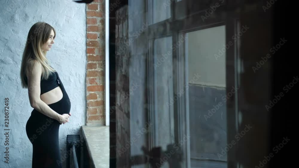 Pregnant is standing by the window Pregnant is standing by the window