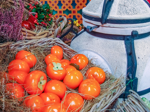 Orange persimmon on a straw in a wicker basket.