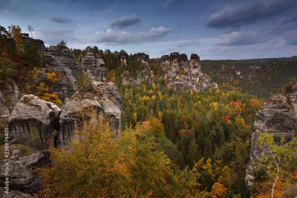 Amazing autumn  landscape in Saxony Bastei Mountains national park. View Exposed sandstone rocks and  forest hilly at sunset. Concept of outdoor recreation in natural settings out of town. 