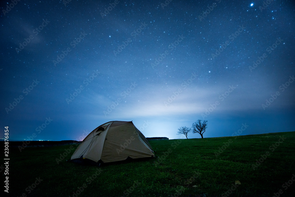 Camping tent in the night mountains under a starry sky