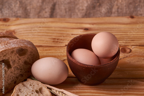 fresh delicious bread, concept for baking. Eggs in clay bowl and wheat sprouts on wooden table