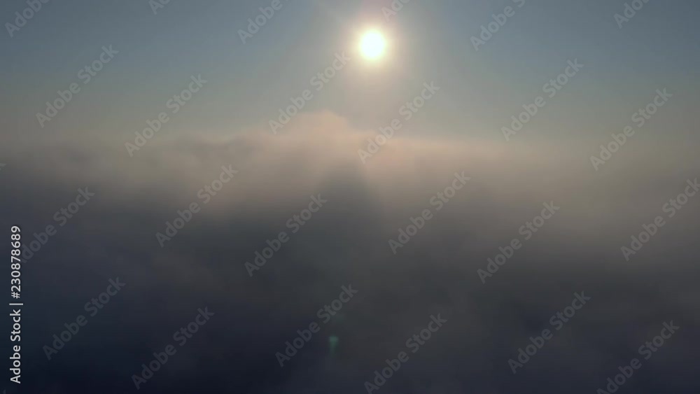 Aerial view over the clouds and sun is shining. Drone flying forward and through while clouds moving. Sun centered above Aerial view over the clouds and sun is shining. Drone flying forward and through while clouds moving. Sun centered above