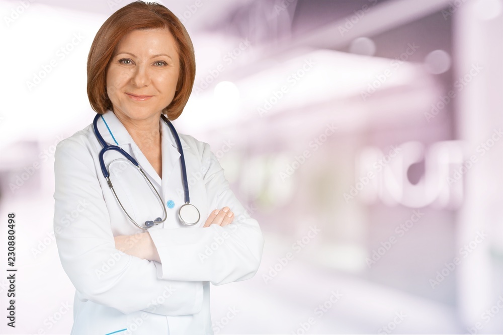 Young female doctor with stethoscope on blurred hospital Young female doctor with stethoscope on blurred hospital