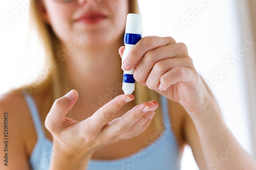 Young woman pricking herself to get a blood sample and perform a glucose test.