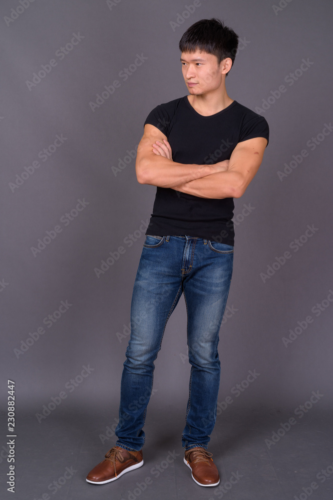 Studio shot of young Chinese man against gray background Studio shot of young Chinese man against gray background