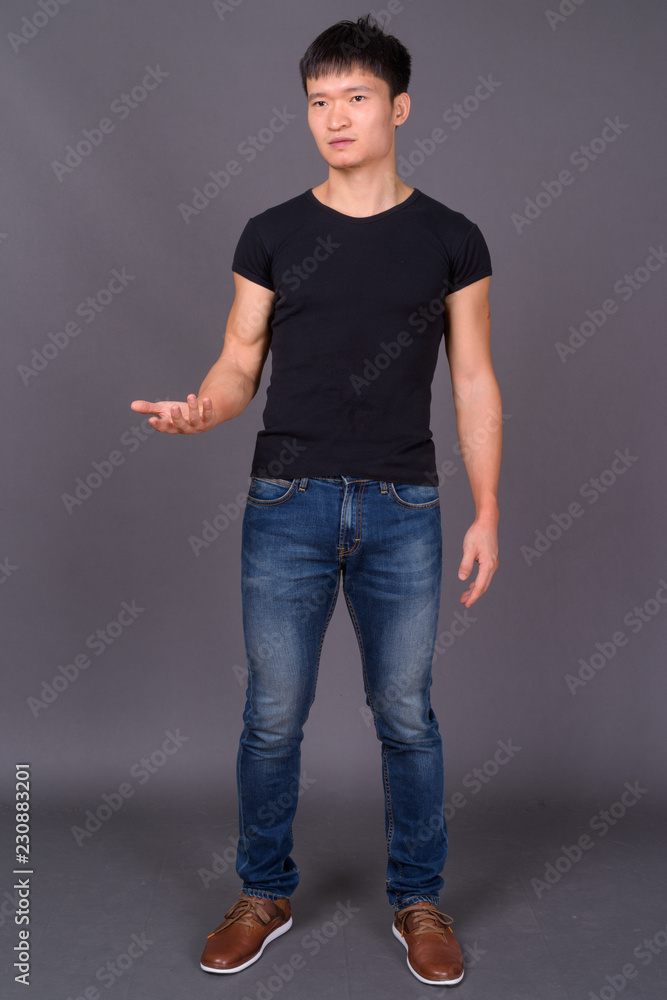Studio shot of young Chinese man against gray background Studio shot of young Chinese man against gray background