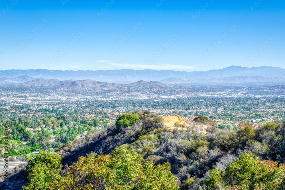 Dirt road above inland city of California with houses and blue sky