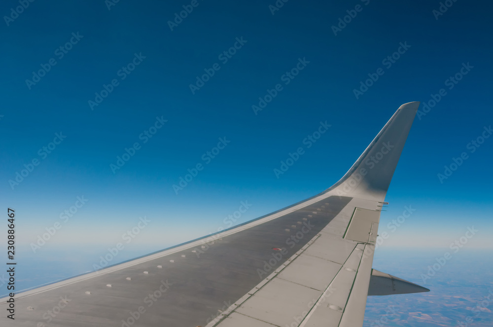 Airplane wing flying in blue sky