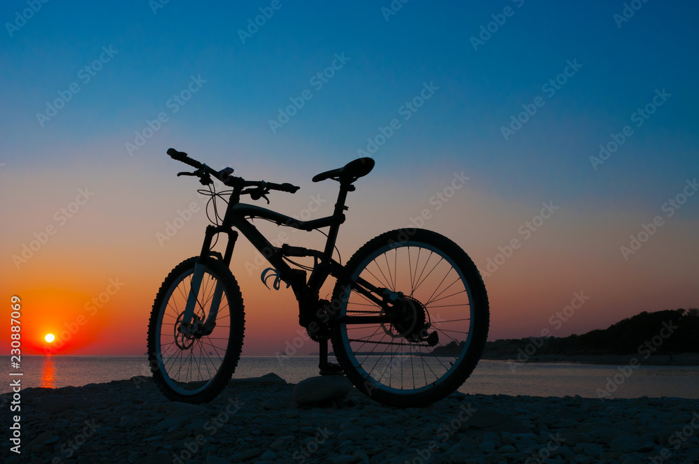 Silhouette of mountain bicycle against sunset at the seacoast