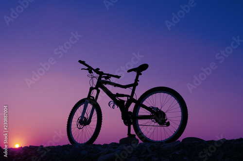 Silhouette of mountain bicycle against sunset. Toned image