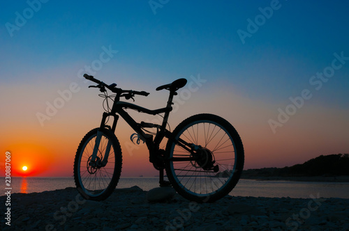 Fototapeta Naklejka Na Ścianę i Meble -  Silhouette of mountain bicycle against sunset at the seacoast