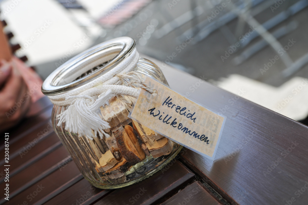 Tischdeko deko glas mit baumscheiben und kleingeld und anhänger herzlich  willkommen cafe restaurant biergarten Stock Photo | Adobe Stock