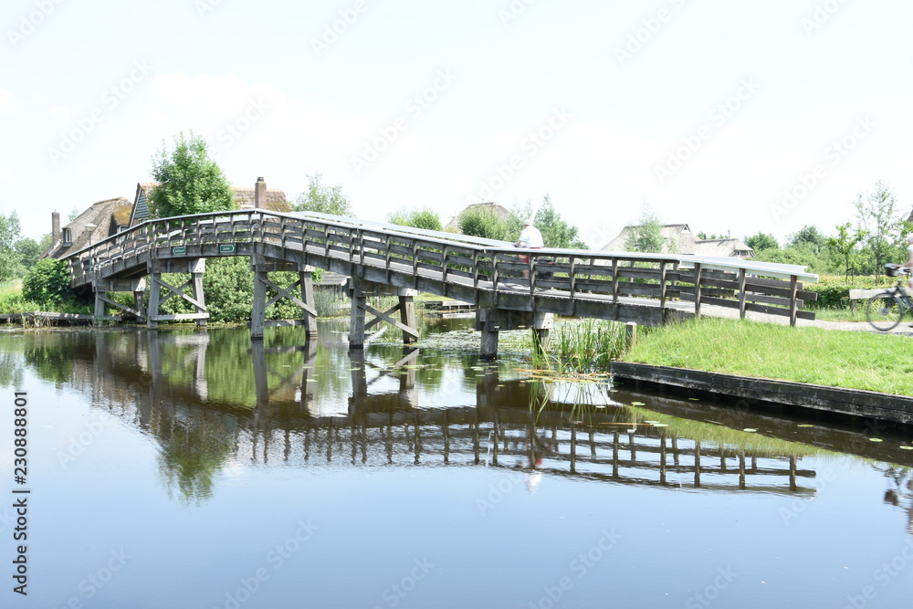Φωτογραφία beschoeid kanaal met fietsbrug en boerderijen met rieten daken in de buurt van G