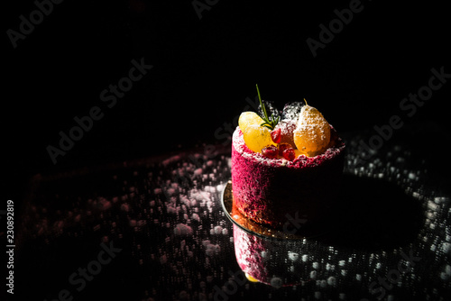 Tasty red cake with fruit on a black background