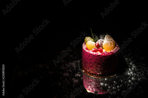 Tasty red cake with fruit on a black background