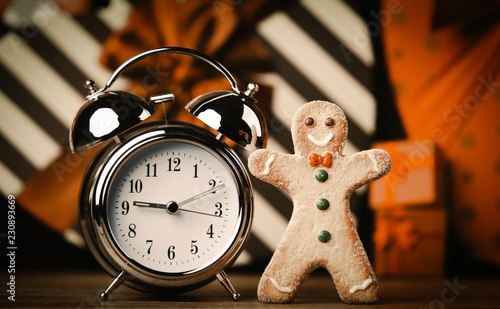 Gingerbread man and alarm clock with gifts on background
