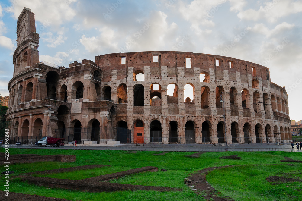 ruins of antique Colosseum with green grass lawn in sunise lights, Rome Italy