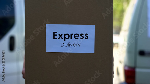 Express delivery courier in uniform holding cardboard box international shipment