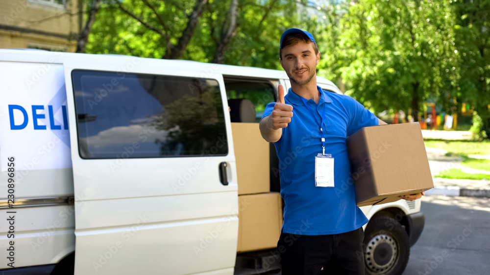 Postal office worker taking parcel box from delivery van and showing thumbs up Postal office worker taking parcel box from delivery van and showing thumbs up