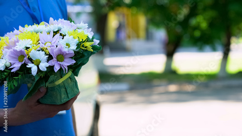 Male courier holding beautiful bouquet, express flowers order and delivery