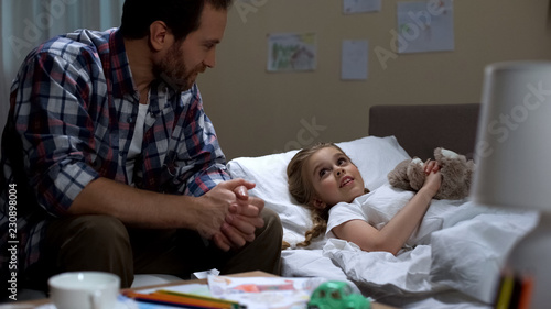 Father telling daughter fairytale before sleep, happy childhood, togetherness