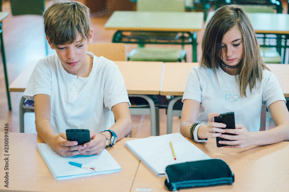 Fototapeta premium Couple young students with smartphone at school