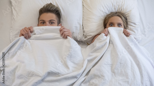 Fotografía Lovers caught in bed by parents, embarrassed and frightened, looking shocked