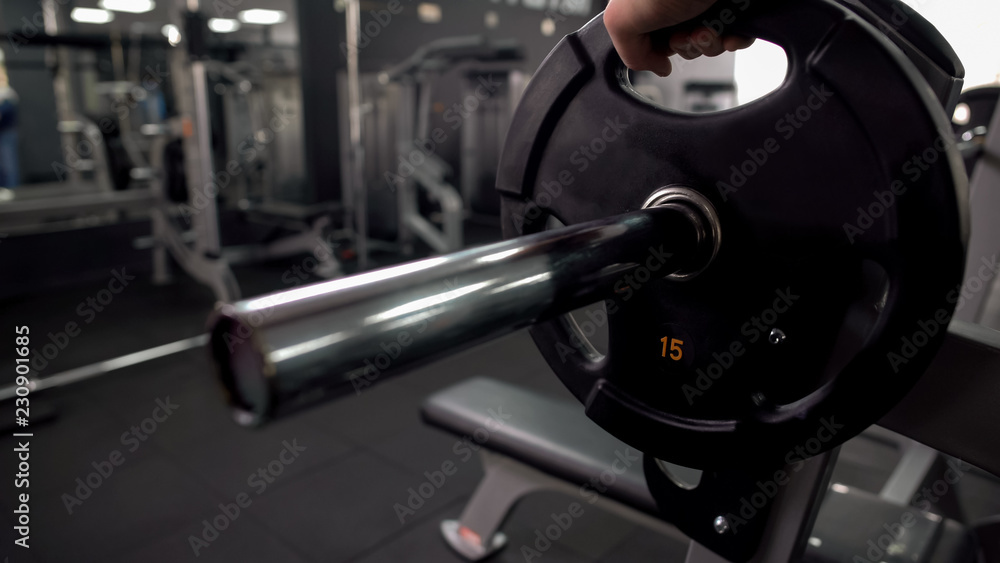 Gym worker adding weight plate barbell, checking equipment, high quality service Gym worker adding weight plate barbell, checking equipment, high quality service