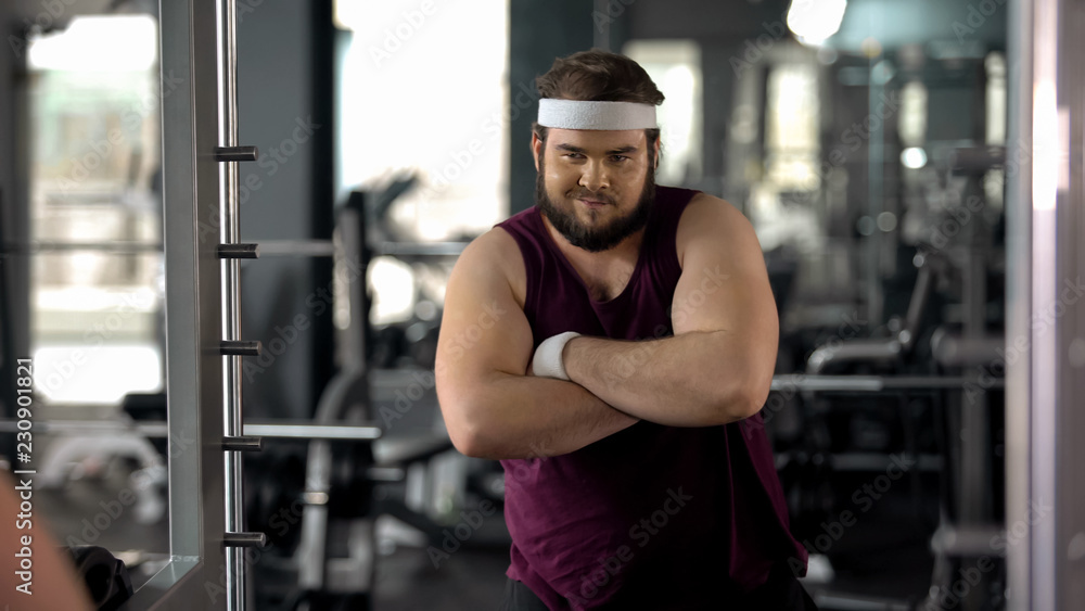 Fat man with folded hands looking at mirror, satisfied with weight loss results Fat man with folded hands looking at mirror, satisfied with weight loss results