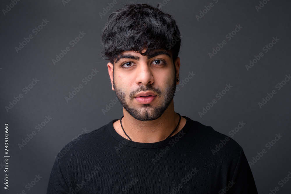 Young handsome Indian man against gray background Young handsome Indian man against gray background